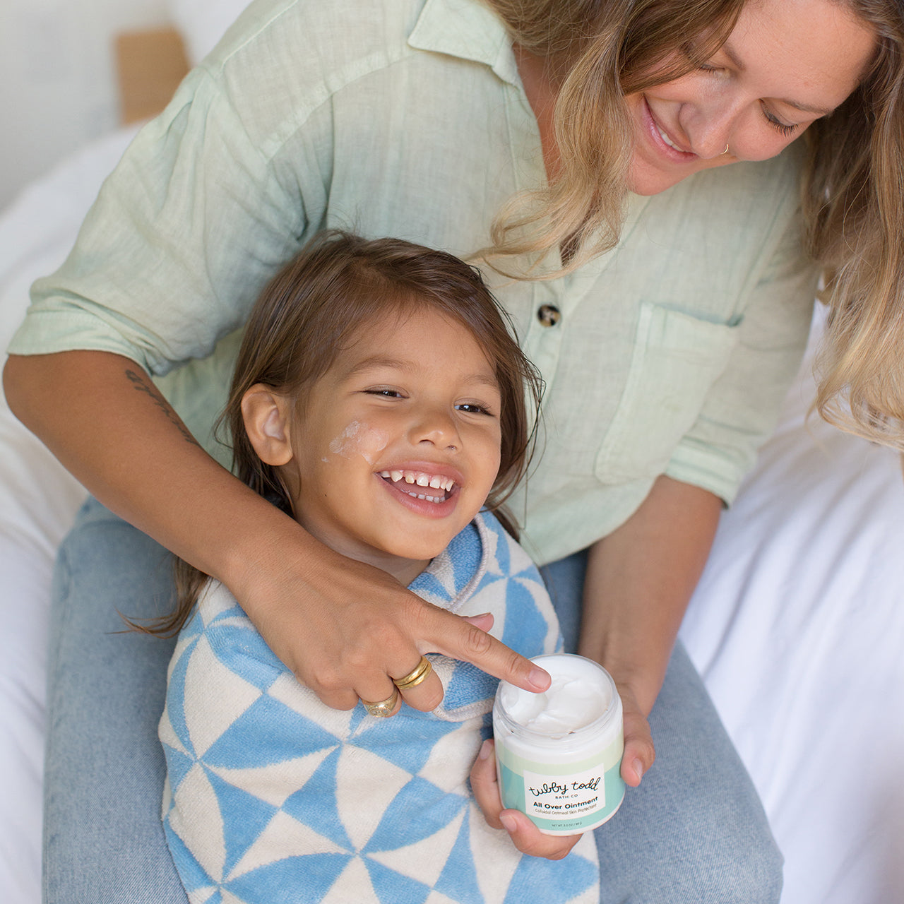 Mom applying All Over Ointment on her kid's face.